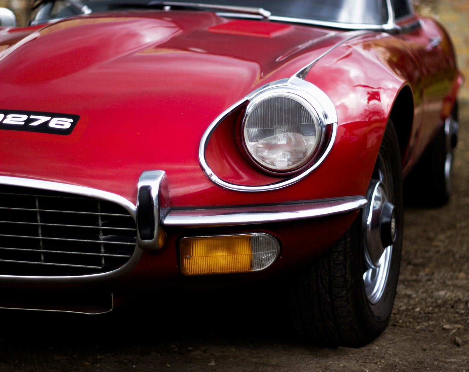 Front view of a red Jaguar classic car featuring a prominent headlight and grille, embodying timeless elegance and craftsmanship