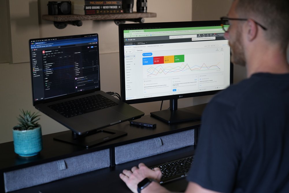 over-the-shoulder-looking-at-two-digital-marketing-monitors-google-ads-analytics