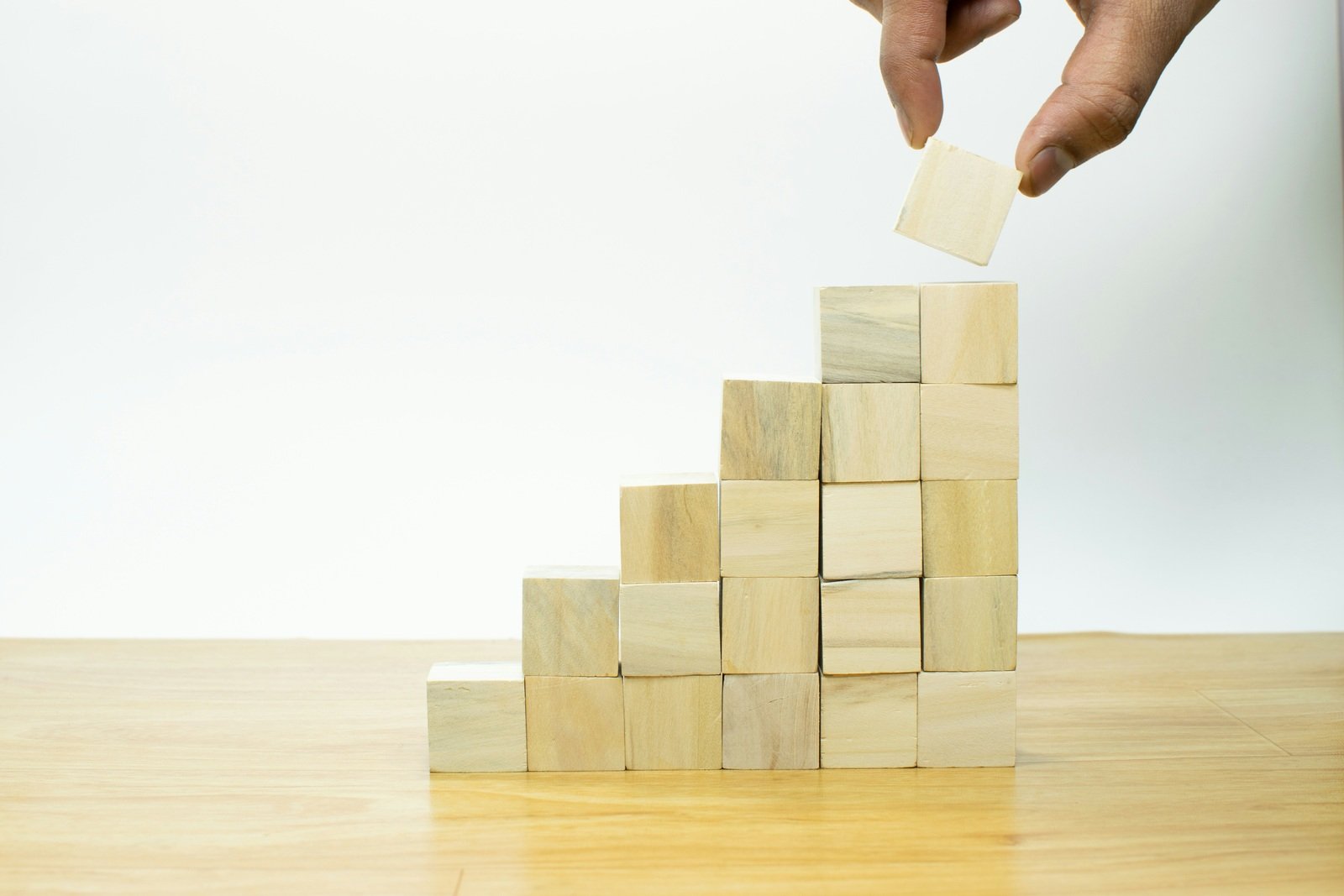 hand-placing-wooden-blocks-to-build-stair-like-structure