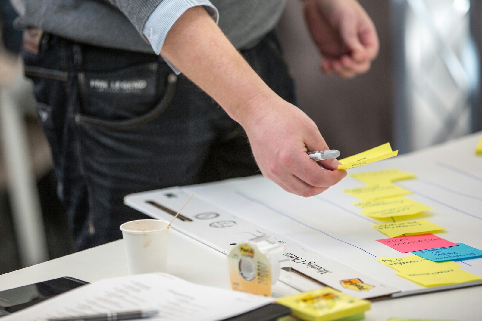 person-organizing-ideas-with-yellow-and-pink-sticky-notes