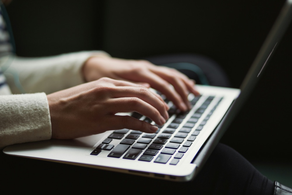 Person typing blog content on a laptop, adding their own knowledge to an AI-assisted draft
